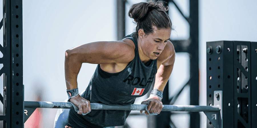 Atleta feminina de CrossFit concentrada executando muscle-ups numa barra de ginástica, demonstrando força e determinação.
