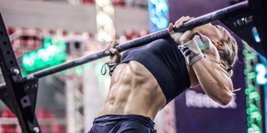 Atleta feminina realizando chest em uma barra de CrossFit, demonstrando força e foco, com seus músculos das costas e braços claramente definidos, enfatizando a intensidade do treinamento.