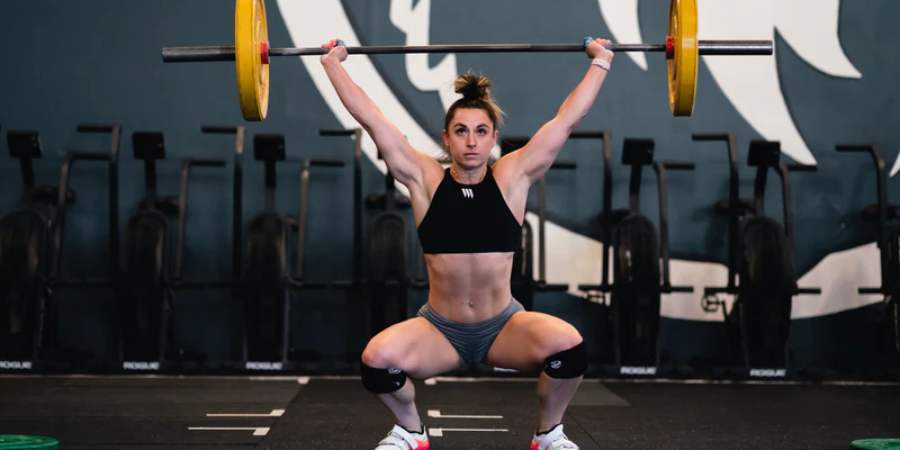 Mulher fazendo squat snatch em uma box de CrossFit.