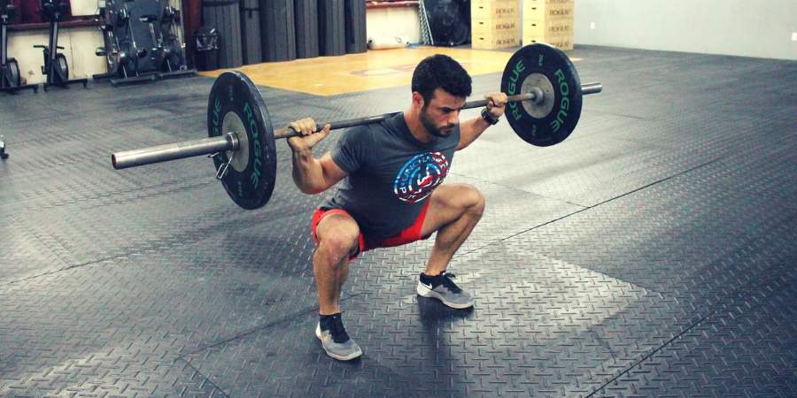 Uma pessoa fazendo back squat em uma box de CrossFit.