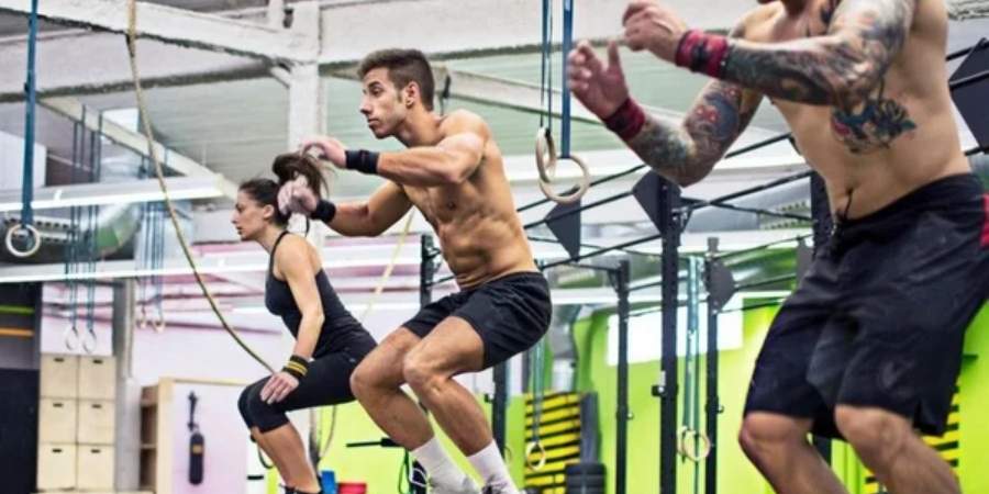 Atletas de CrossFit em ação, praticando saltos box e exercícios de agilidade em um ambiente de box de CrossFit dinâmico e bem equipado.